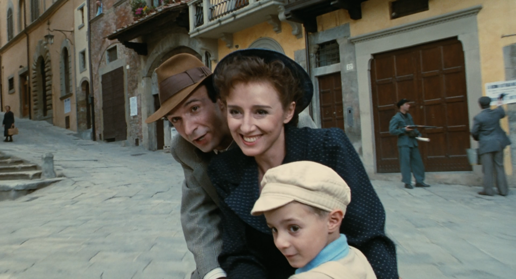 La vita è bella Roberto Benigni, Nicoletta Braschi e il piccolo Giorgio Cantarini in una scena del film / Foto: Lettore.org
